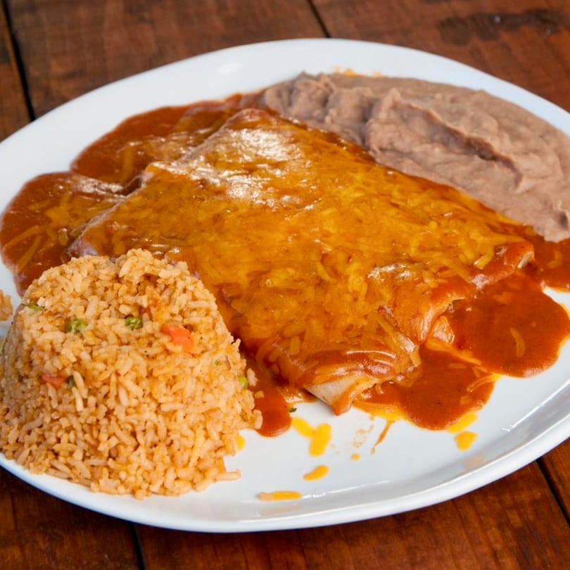Two cheese enchiladas covered in red sauce and melted cheese, with rice and refried beans.